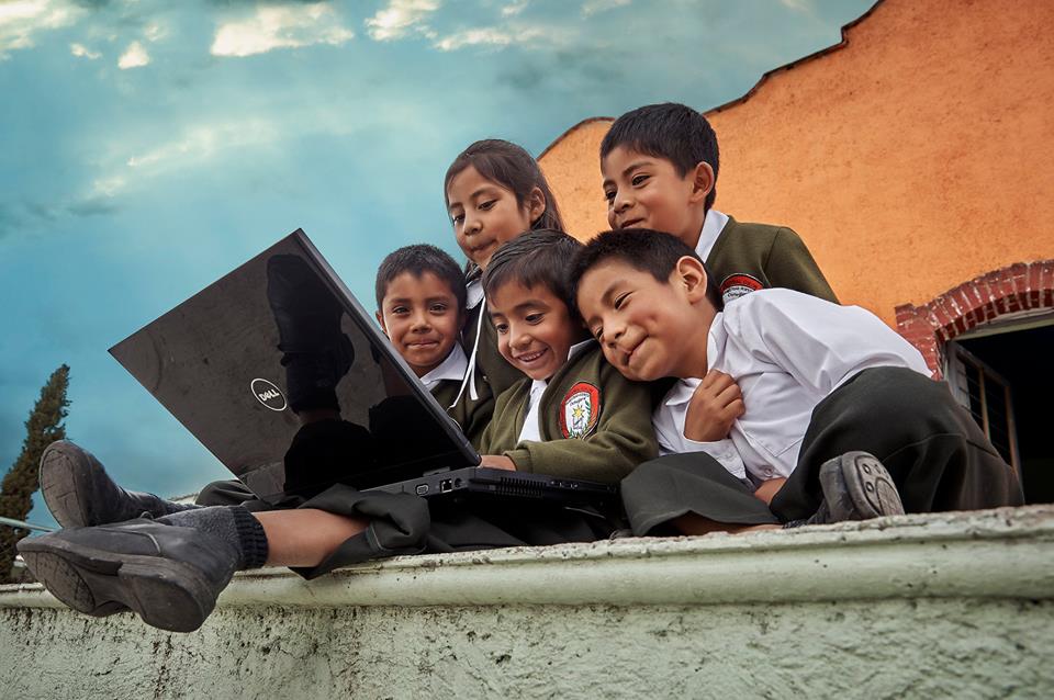 Grupo de niños y niñas mirando una computadora juntos.