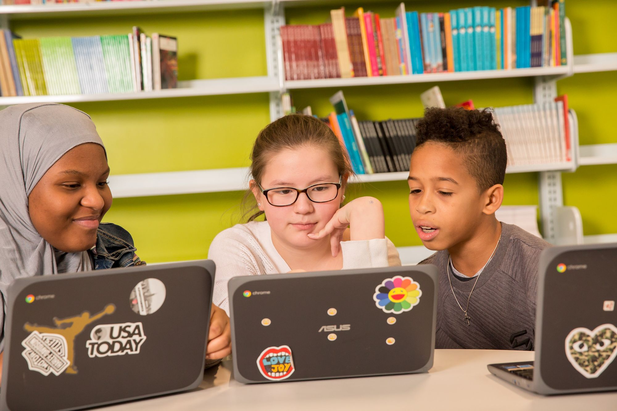Three young students learn online together.