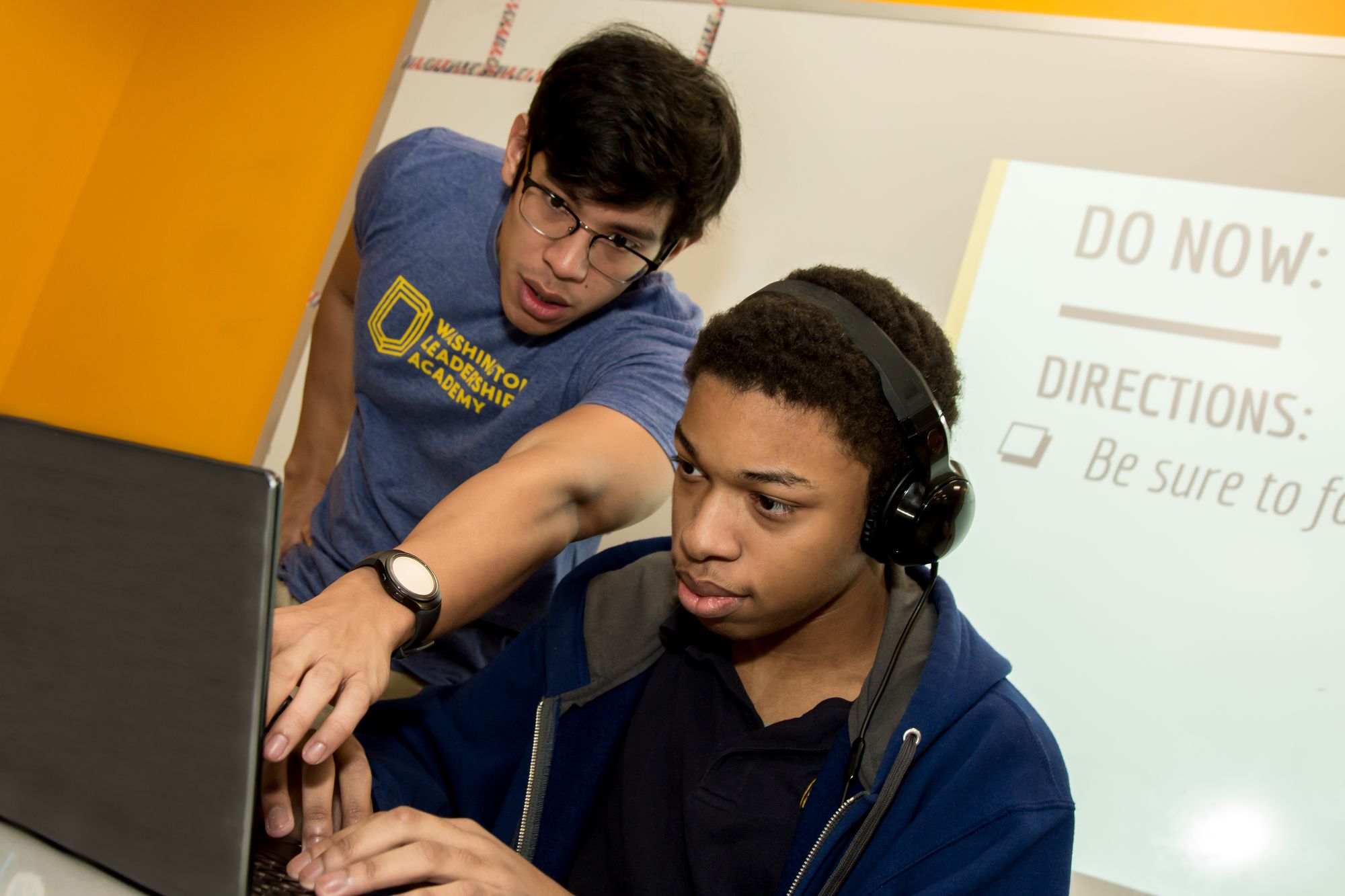 Teacher pointing to laptop while student is reading a short science fiction story