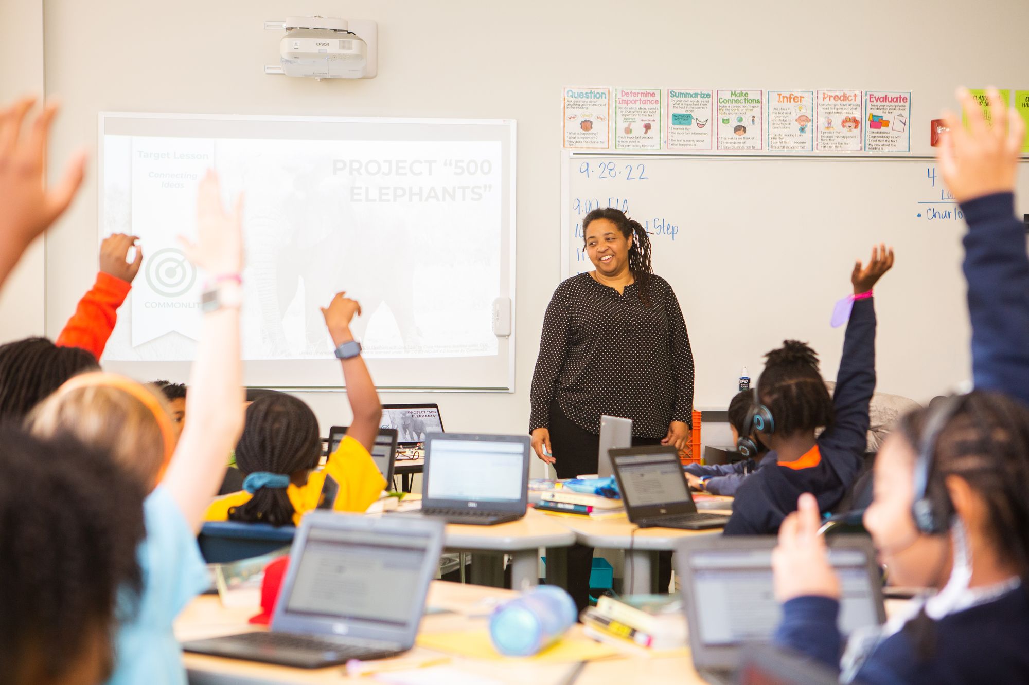 Students raise their hand in a classroom to answer a question about a CommonLit lesson.