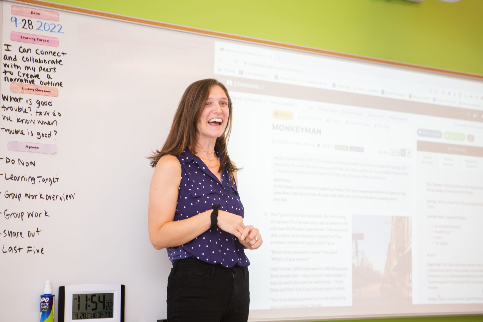 Smiling female learning facilitator standing in front of a whiteboard in a classroom